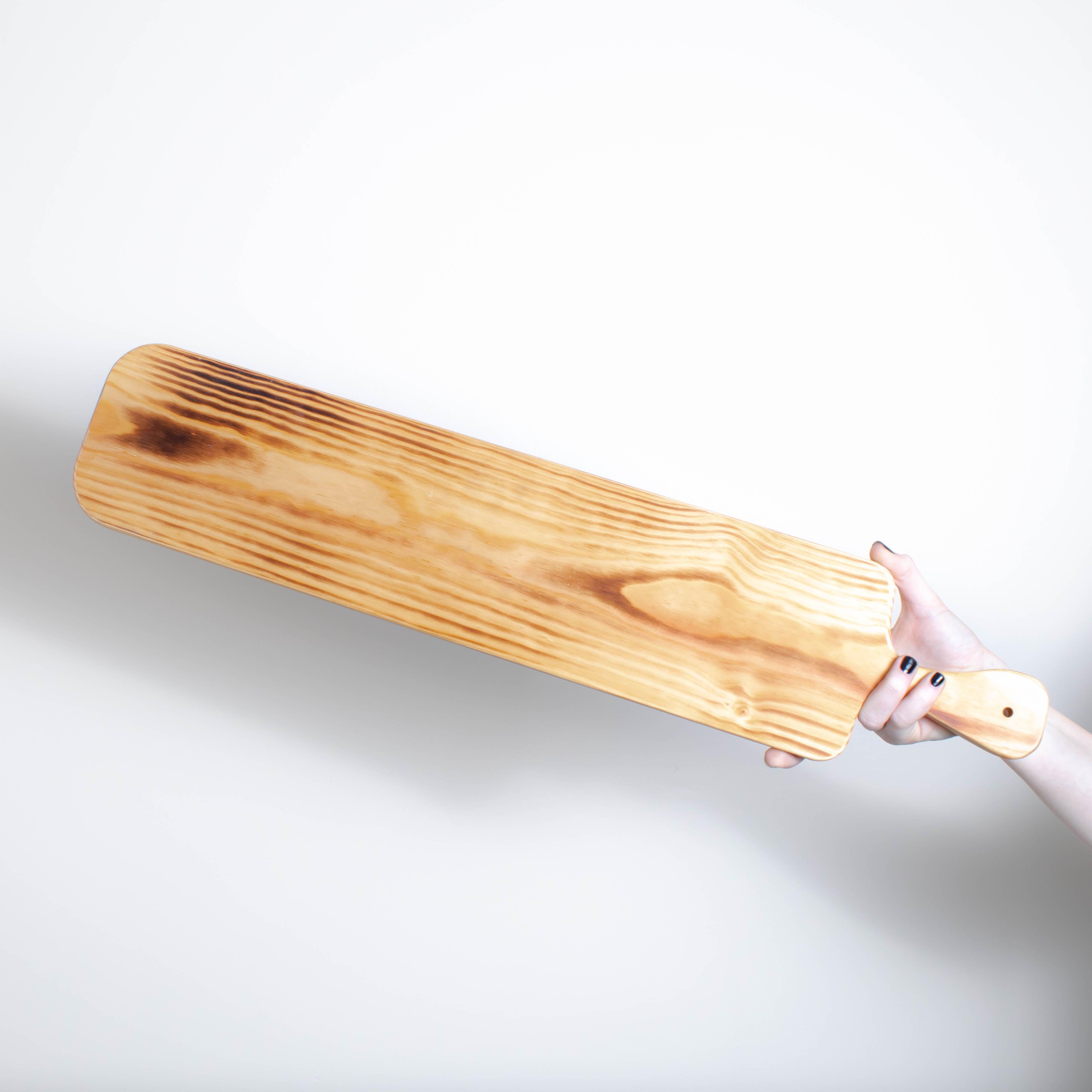 A person holding a Bespoke 77 Medium Pine Serving Board / Sharing Board in front of a white wall.